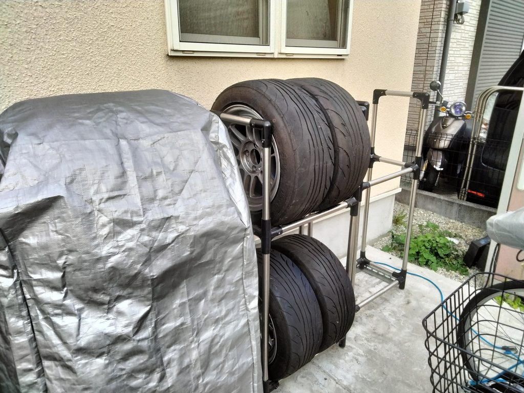 自宅の屋外でタイヤラック2台を並べてカバーありとカバーなしで保管した状態